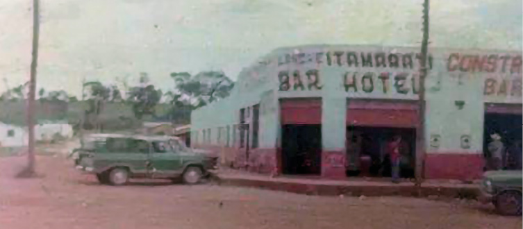 Imagem paisagem de um esquina de um bar. Na frente do estabelecimento tem um carro verde.